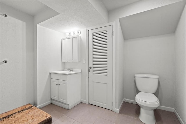 bathroom featuring vanity, toilet, baseboards, and tile patterned flooring