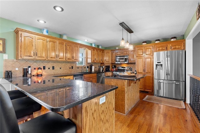 17701 C Hwy, Trimble, MO 64492 - kitchen featuring appliances with stainless steel finishes, light wood-style floors, a breakfast bar area, a peninsula, and dark countertops