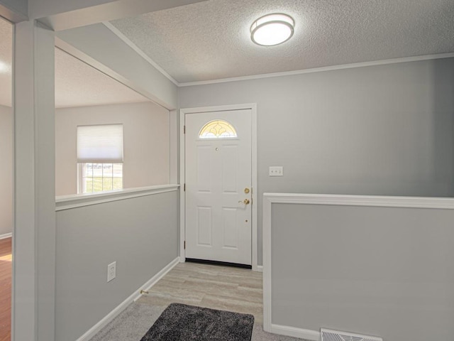 entrance foyer featuring visible vents, baseboards, a textured ceiling, and ornamental molding