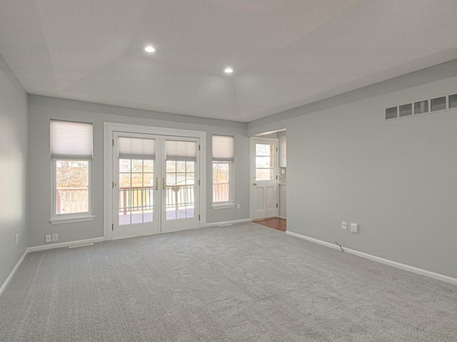 carpeted empty room with visible vents, a raised ceiling, recessed lighting, french doors, and baseboards