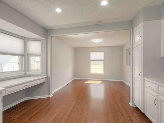 spare room featuring dark wood finished floors, visible vents, a textured ceiling, and baseboards