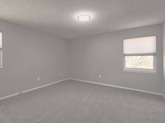 spare room with carpet flooring, baseboards, and a textured ceiling