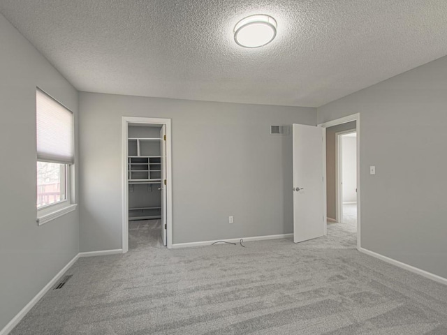 unfurnished bedroom with visible vents, baseboards, a spacious closet, and carpet flooring