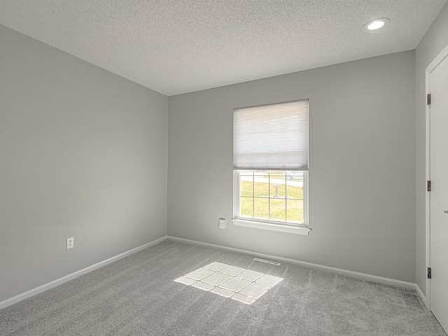 unfurnished room with carpet flooring, baseboards, and a textured ceiling