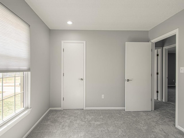 unfurnished bedroom with a textured ceiling, baseboards, and carpet floors