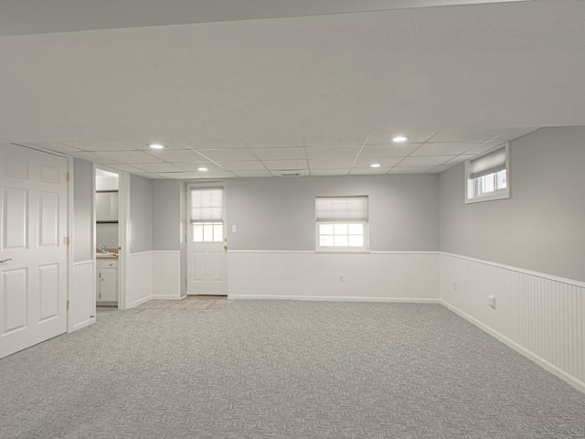 below grade area featuring a wealth of natural light, wainscoting, and carpet