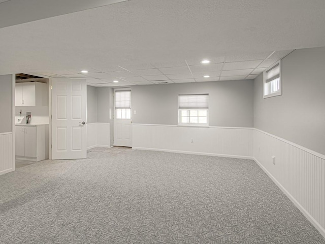 basement featuring light carpet and wainscoting