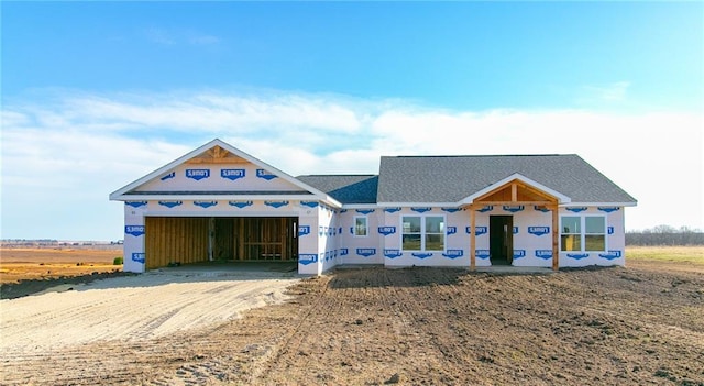 property in mid-construction with an attached garage and dirt driveway