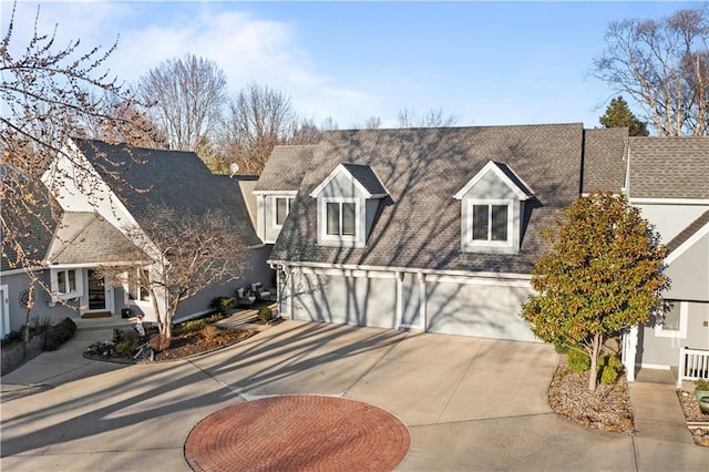 new england style home with a garage, roof with shingles, and driveway