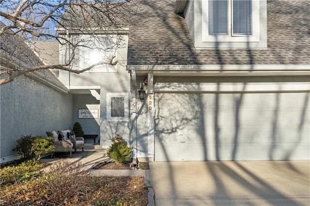 property entrance featuring stucco siding, concrete driveway, an attached garage, and a shingled roof