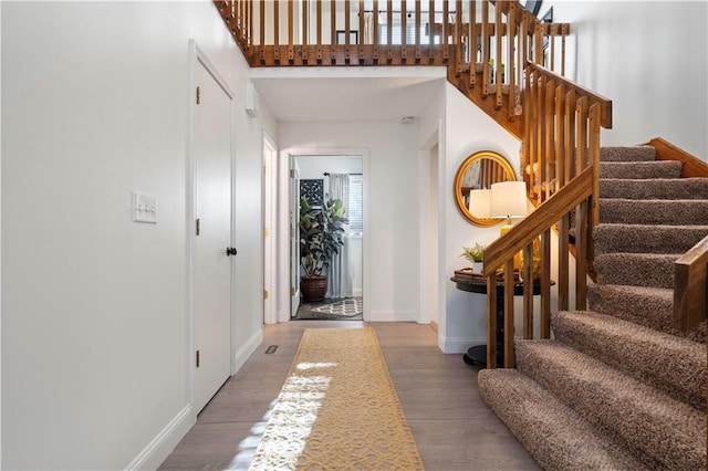 entryway with baseboards, a high ceiling, wood finished floors, and stairs