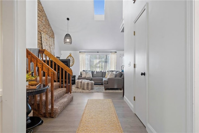 interior space with a skylight, stairway, wood finished floors, and a towering ceiling