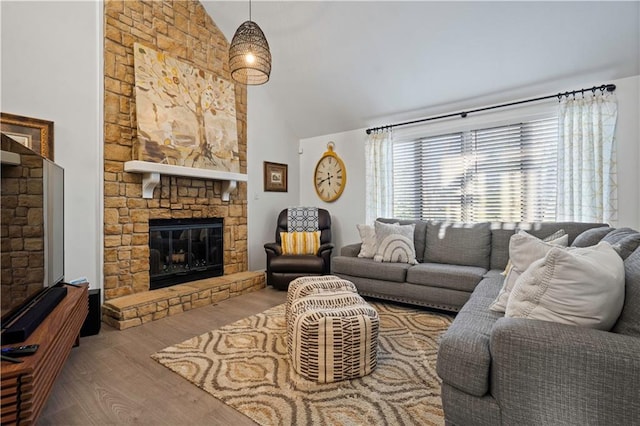 living area with high vaulted ceiling, wood finished floors, and a fireplace