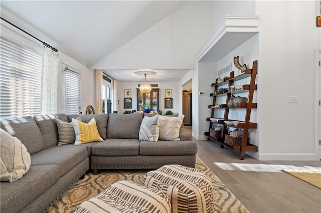 living area with baseboards, high vaulted ceiling, an inviting chandelier, and wood finished floors