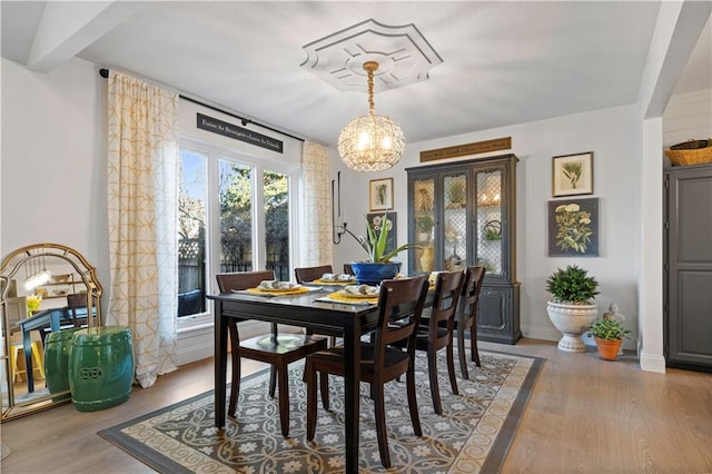 dining space with beamed ceiling, wood finished floors, baseboards, and a chandelier