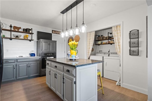 kitchen featuring black oven, a kitchen island, gray cabinets, wood finished floors, and open shelves