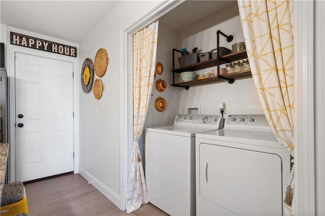 clothes washing area featuring washer and clothes dryer, baseboards, and wood finished floors