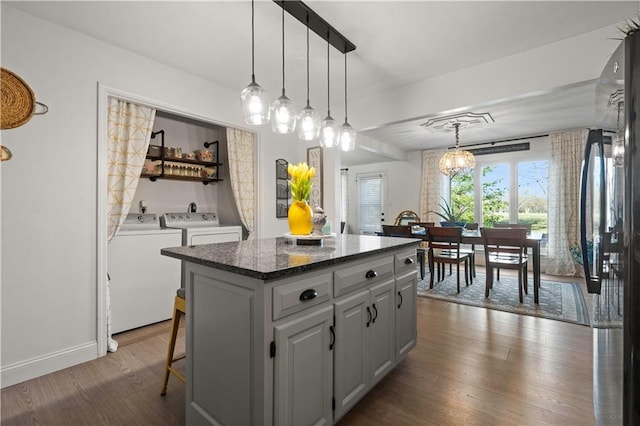 kitchen featuring a kitchen island, dark wood-type flooring, white cabinets, decorative light fixtures, and washing machine and dryer