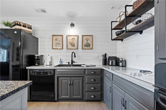 kitchen with open shelves, visible vents, black appliances, and a sink