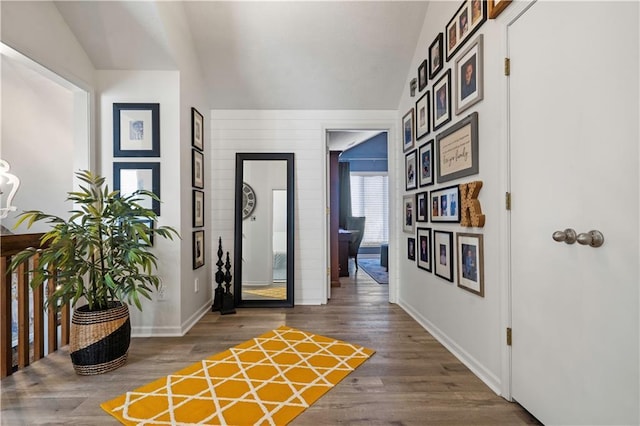 corridor with vaulted ceiling, baseboards, and wood finished floors