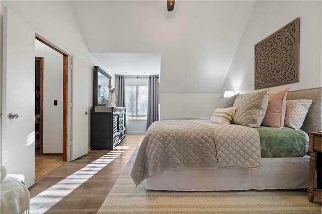 bedroom with a ceiling fan, vaulted ceiling, wood finished floors, and baseboards