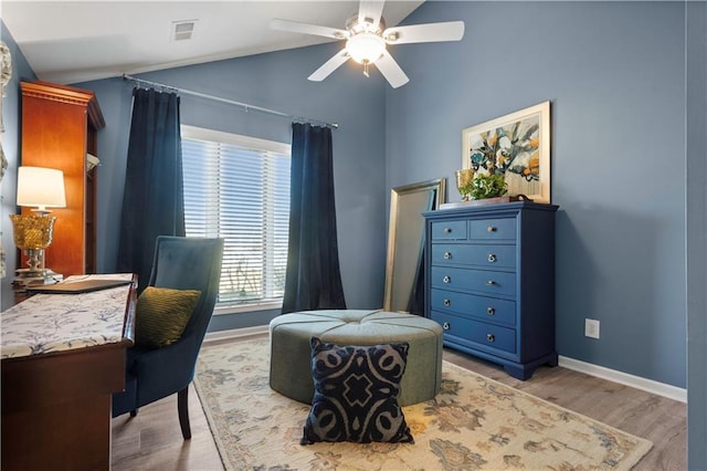 sitting room with baseboards, visible vents, light wood finished floors, lofted ceiling, and ceiling fan