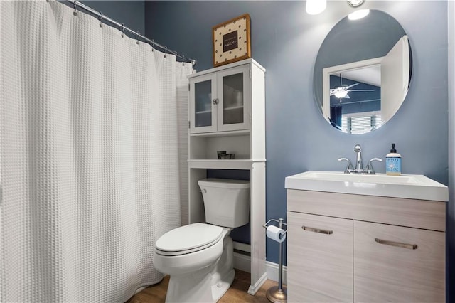 bathroom featuring baseboards, toilet, wood finished floors, and vanity