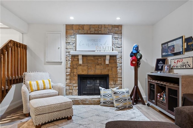 living area with recessed lighting, baseboards, a stone fireplace, and wood finished floors