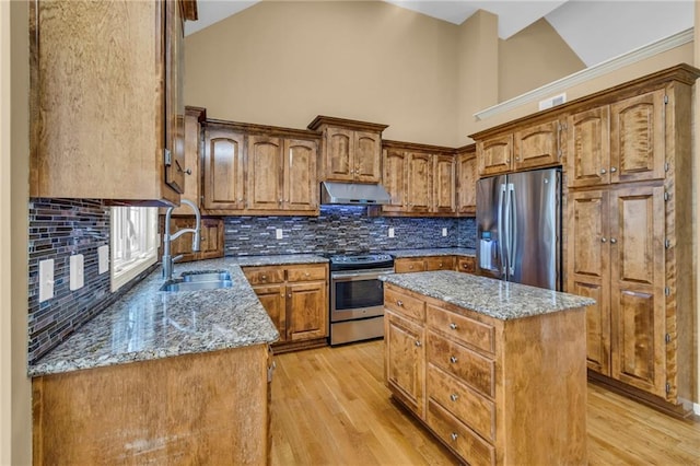 kitchen with a sink, light stone countertops, extractor fan, and appliances with stainless steel finishes