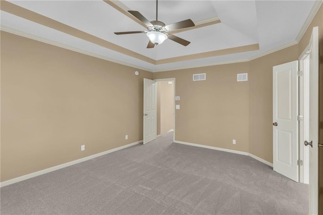 carpeted empty room featuring a raised ceiling, a ceiling fan, visible vents, and ornamental molding