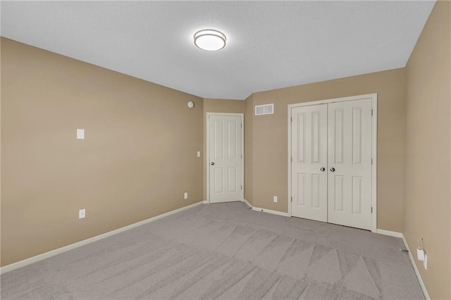 unfurnished bedroom featuring baseboards, visible vents, carpet floors, and a closet