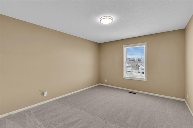 carpeted spare room featuring visible vents, baseboards, and a textured ceiling