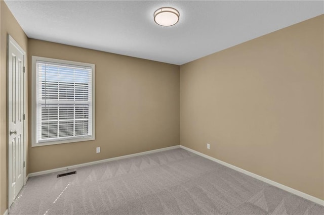 carpeted empty room featuring visible vents and baseboards