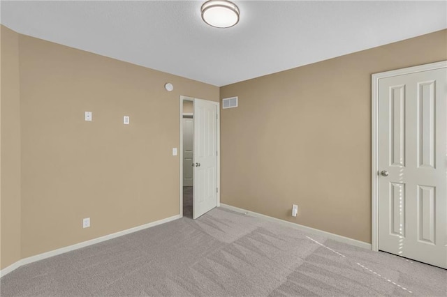 unfurnished room featuring baseboards, visible vents, and light carpet