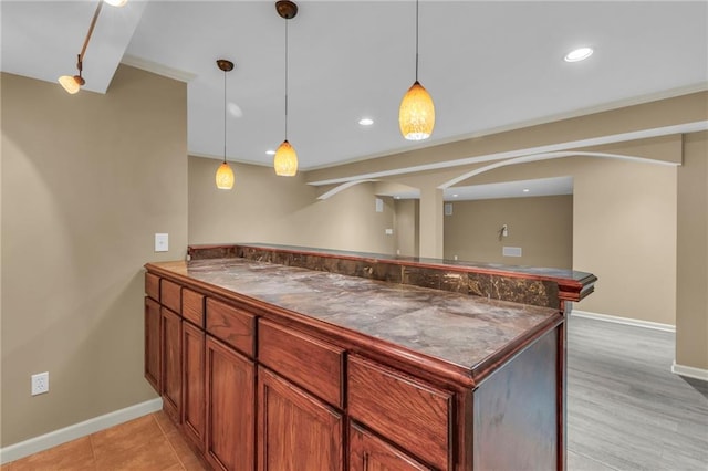 kitchen with dark countertops, decorative light fixtures, a peninsula, and baseboards