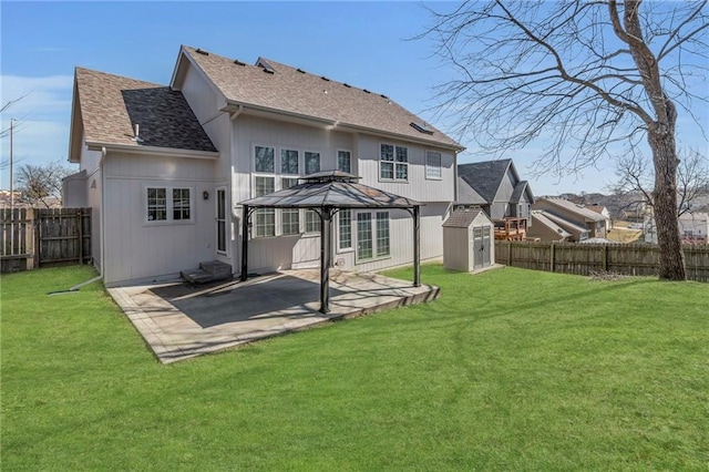 back of property featuring a shingled roof, a yard, an outbuilding, a storage unit, and a patio