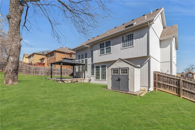 rear view of house with a gazebo, a lawn, and a fenced backyard