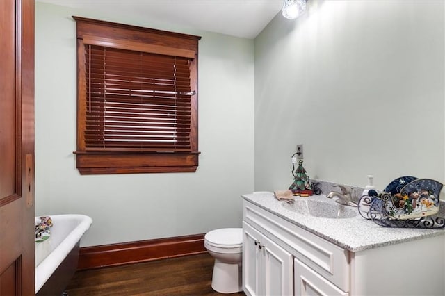 209 High St, Platte City, MO 64079 - bathroom with vanity, wood finished floors, baseboards, a freestanding bath, and toilet