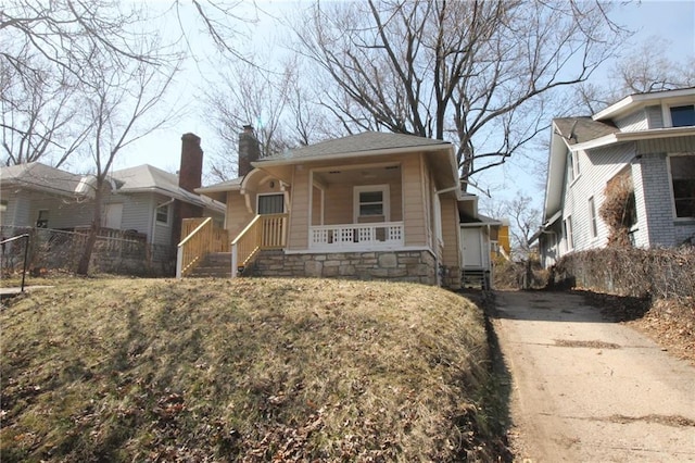 view of front of home with a porch, a chimney, and fence