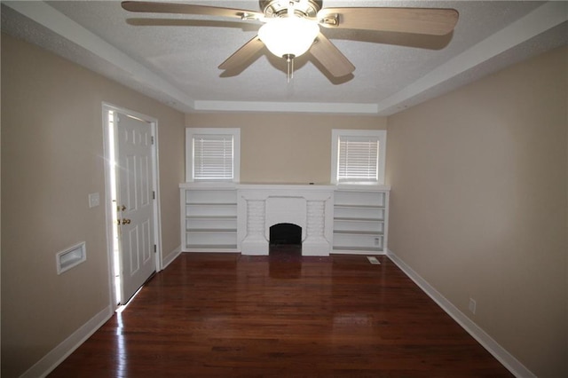 unfurnished living room featuring a brick fireplace, wood finished floors, baseboards, and a textured ceiling