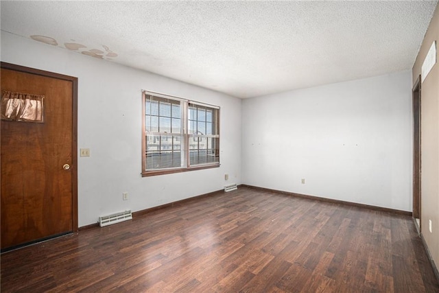 empty room with visible vents, a textured ceiling, baseboards, and wood finished floors