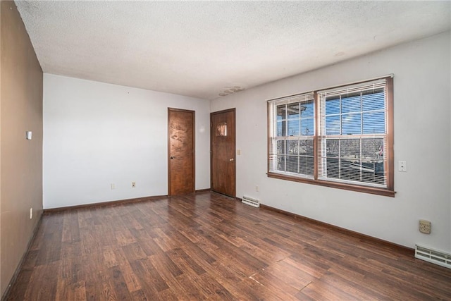 unfurnished room featuring wood finished floors, visible vents, and a textured ceiling