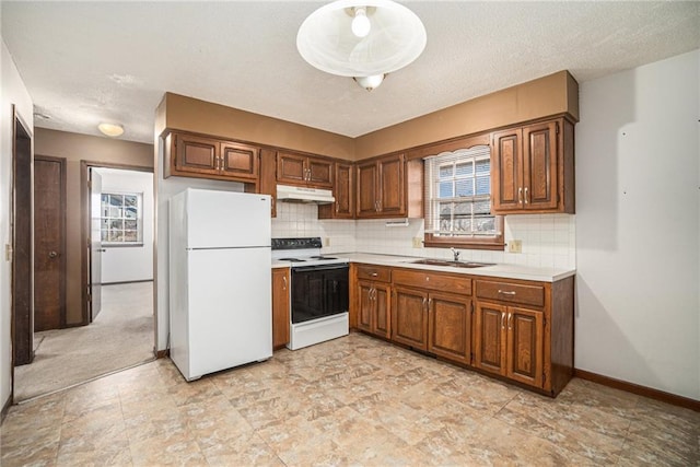 kitchen with under cabinet range hood, a sink, tasteful backsplash, white appliances, and light countertops