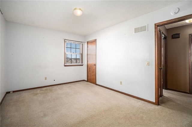 carpeted spare room featuring visible vents, baseboards, and a textured ceiling