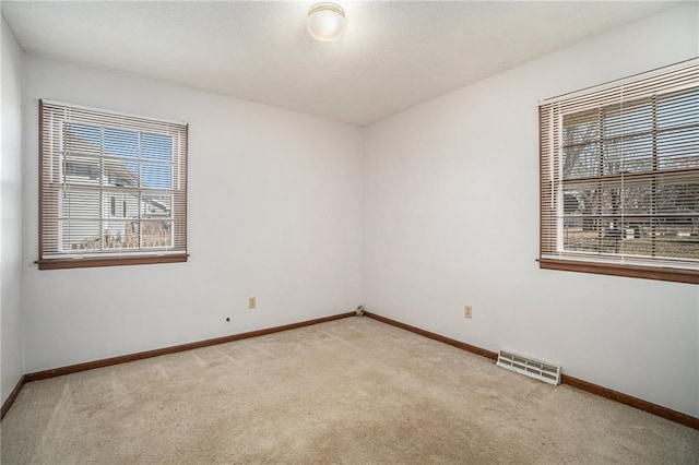 carpeted empty room with baseboards, visible vents, and a textured ceiling