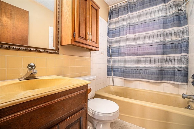 full bath featuring tile walls, toilet, shower / bath combo with shower curtain, a textured ceiling, and vanity