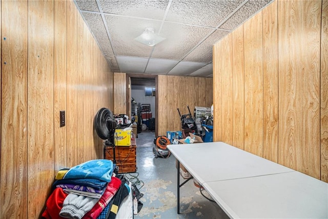 interior space with a paneled ceiling and wood walls