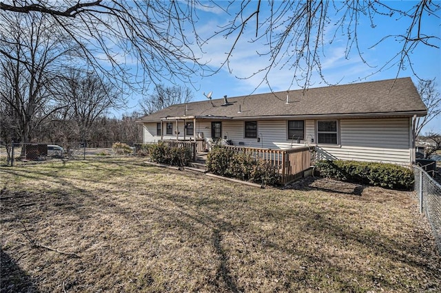 back of property with a fenced backyard, a lawn, roof with shingles, and a wooden deck