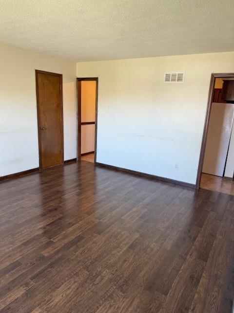 1507 W Concord Dr, Plattsburg, MO 64477 - spare room with dark wood-type flooring, visible vents, baseboards, and a textured ceiling