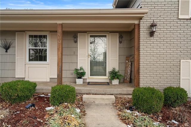 doorway to property featuring brick siding and covered porch